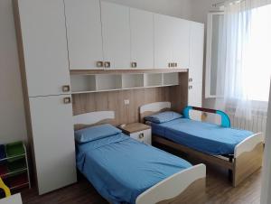 twee bedden in een kamer met blauwe lakens bij Bright and cozy apartment in Sesto San Giovanni