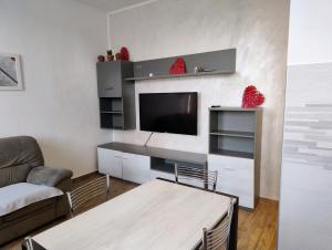 een woonkamer met een tv, een bank en een tafel bij Bright and cozy apartment in Sesto San Giovanni