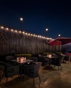 un patio con tavoli e sedie e una recinzione di notte di Haven Hotel Sector 31,Gurugram a Gurgaon