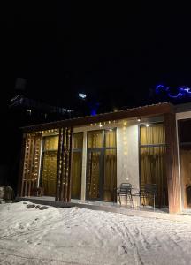een gebouw met een tafel en stoelen in de sneeuw bij Villa Cielo Mestia in Mestia