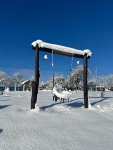 a swing with snow on it in a snow covered field at Tea House Ponoarele in Ponoarele