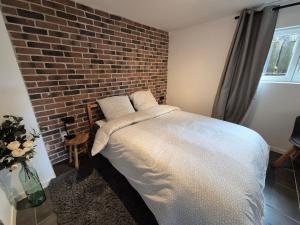 a bedroom with a bed against a brick wall at Le Loft Des Cigognes in Barr