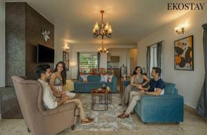 een groep mensen die in een woonkamer zitten bij EKOSTAY - Skyfall Mist Villa in Ooty