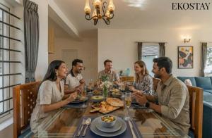 een groep mensen die rond een tafel zitten te eten bij EKOSTAY - Skyfall Mist Villa in Ooty