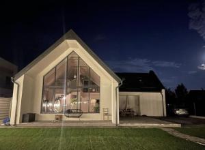 una casa con una grande finestra in un cortile di notte di Pineview Lempes a Braşov