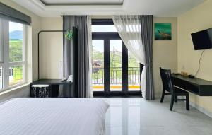 a bedroom with a bed and a desk and a window at Flamingo Villa Hoi An in Hoi An