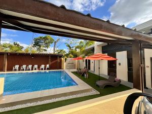 einen Pool mit Sonnenschirm und Stühlen neben einem Haus in der Unterkunft Dano Private Resort and Apartments in Dauis