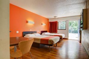 2 letti in una camera con pareti arancioni e tavolo di Motel 6-Kansas City, MO a Kansas City