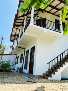 a white house with stairs and a balcony at VILLA Sea La THALPE in Talpe