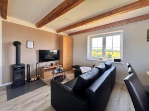 un soggiorno con divano nero e stufa a legna. di Ferienwohnungen Reutergut a Eibenstock