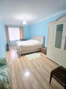 a bedroom with a white bed and a wooden floor at уют in Rustavi