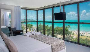 a bedroom with a bed with a view of the ocean at Acqua Suítes Maceió in Maceió