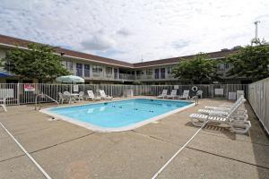 a pool with chaise lounge chairs and a fence at Motel 6-Amherst, OH - Cleveland West - Lorain in Amherst