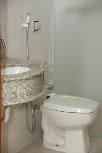 y baño con aseo blanco y lavamanos. en Itália Hotel, en Fernandópolis