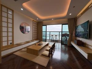 a living room with a table and a large window at QNC Taiyo Homestay in Hai Phong