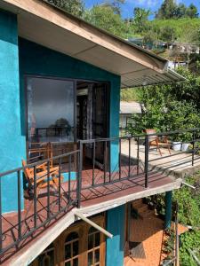 Dieses blaue Haus verfügt über einen Balkon mit einem Tisch und Stühlen. in der Unterkunft Thumb Up Family Rest in Haputale