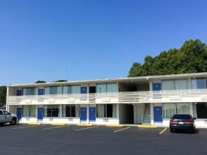 Motel 6-Connellys Springs, NC في هيكوري: مبنى كبير بأبواب زرقاء وموقف سيارات