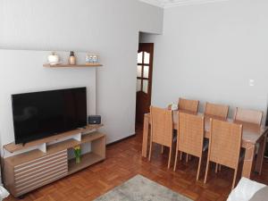 un soggiorno con televisione, tavolo e sedie di Carvalho Apê Centro I Poços de Caldas a Poços de Caldas