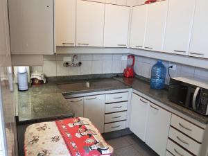 a kitchen with white cabinets and a counter top at Carvalho Apê Centro I Poços de Caldas in Poços de Caldas