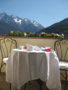 una mesa blanca con sillas y flores en el balcón en Villetta Nembra, en Edolo