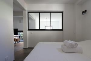 ein weißes Schlafzimmer mit einem Bett und einem Fenster in der Unterkunft Nümad Suites in Nizza