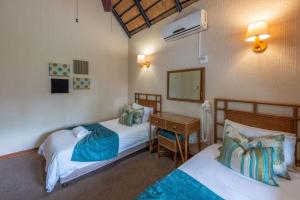 Zimmer mit 2 Betten, einem Schreibtisch und einem Spiegel in der Unterkunft Kruger Park Lodge Unit No. 543 in Hazyview + 38 Fotos