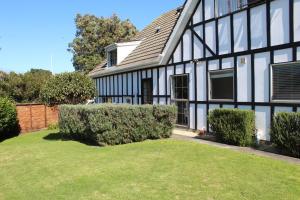 a black and white house with a yard at Tudor Manor Bed & Breakfast in Paraparaumu Beach