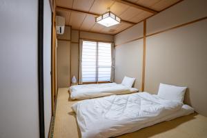 two beds in a room with a window at Guest House Ouka in Takayama