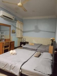 ein Schlafzimmer mit drei Betten, einem Schreibtisch und einem Ventilator in der Unterkunft Idid homestay in Kota Belud