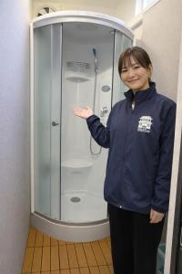 Eine Frau steht vor einer Dusche in der Unterkunft 宿屋しの軒 in Kirishima