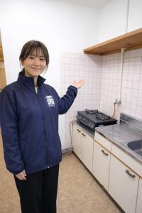 eine Frau steht in einer Küche und posiert für ein Foto in der Unterkunft 宿屋しの軒 in Kirishima