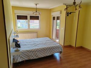 a bedroom with a bed with yellow walls and wooden floors at Casa Seán in Boiro