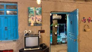 a tv sitting on a table next to a blue door at Byet ahalna in Mūsá