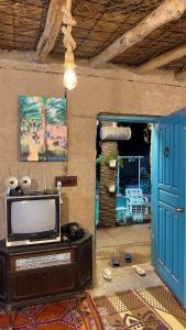 a living room with a tv and a blue door at Byet ahalna in Mūsá