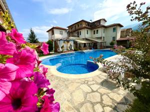 ein Pool vor einem Haus mit rosa Blumen in der Unterkunft Вила Флора Паталеница in Patalenitsa