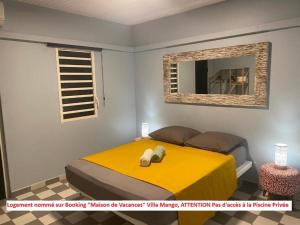 een slaapkamer met een geel bed en een spiegel bij Dez'îles Guadeloupe in Sainte-Anne