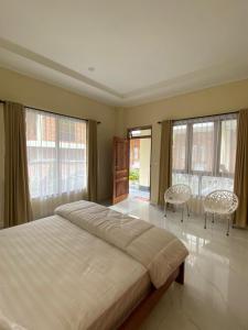 een slaapkamer met een groot bed met 2 stoelen en ramen bij SADAMA Cottage in Tuk Tuk