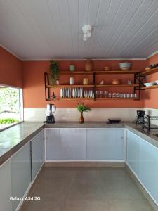 een keuken met witte kasten en oranje muren bij Pousada jks in Porto Seguro