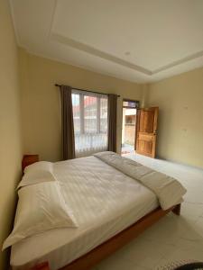 een groot bed in een slaapkamer met een raam bij SADAMA Cottage in Tuk Tuk +4 foto's