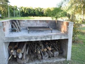 a stone fire pit with a bench and logs at Cabañas Campos del Parana in San Pedro