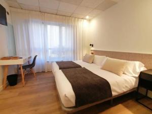 a bedroom with a large bed with a desk and a window at Auditorio Rooms Boutique Oviedo in Oviedo +3 photos