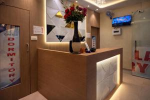 een lobby met een bar met een vaas met bloemen erop bij Relax Kurla Dormitory in Mumbai