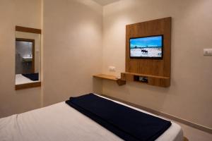 een slaapkamer met een bed en een tv aan de muur bij Relax Kurla Dormitory in Mumbai +12 foto's
