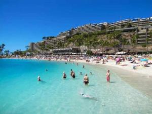 een groep mensen in het water op een strand bij Moguel Canarian Holiday 1º in Arguineguín