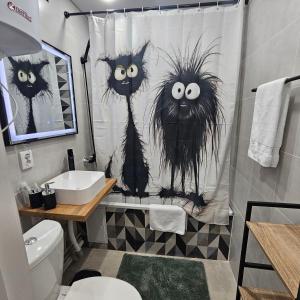 a bathroom with a shower curtain with two cats on it at Глинки 1комн in Semey