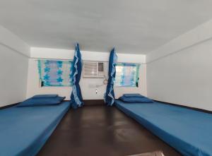 une chambre avec deux lits et deux fenêtres dans l'établissement Ezekiel Transient House, à Coron