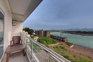 een balkon met een bank en uitzicht op een rivier bij Sai Unity Boutique Stay in Garudeshwar