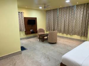 a bedroom with a bed and a desk and a tv at Manab Palace in Kendrāparha