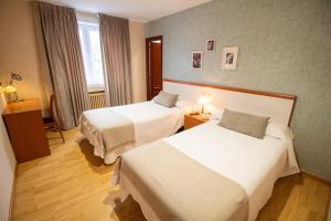 ein Hotelzimmer mit zwei Betten und einem Fenster in der Unterkunft Hotel Montero in Mondoñedo