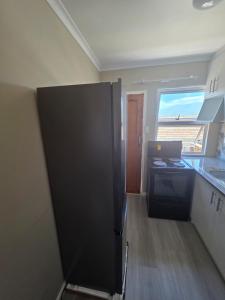 een keuken met een zwarte koelkast en een raam bij Chaudhray accommodation in George